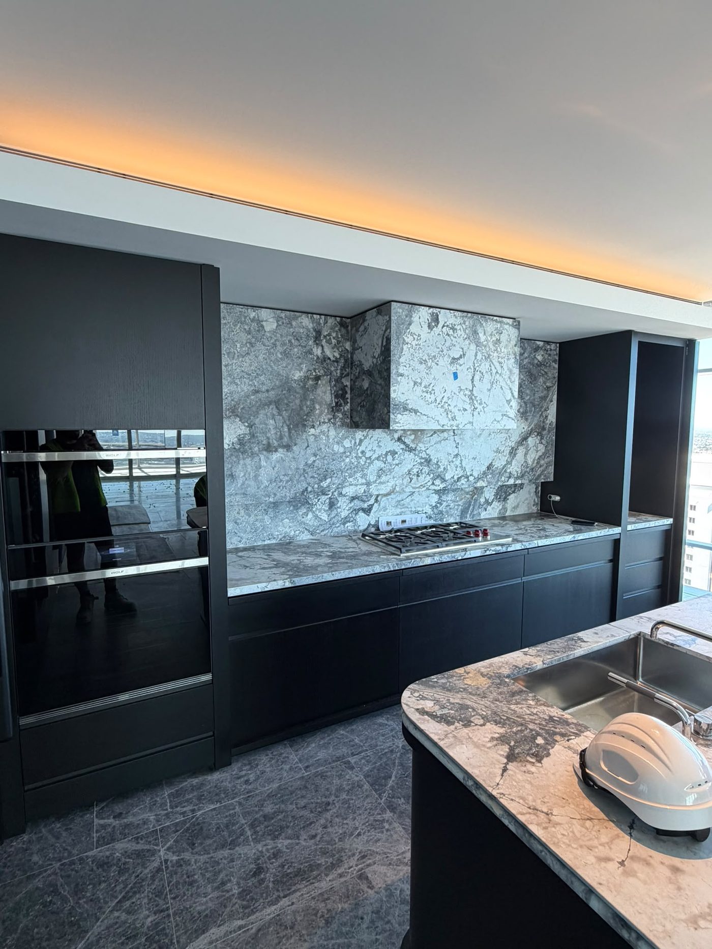 Kitchen renovation by Alta-Reno Services — dark cabinetry and marble splashback
