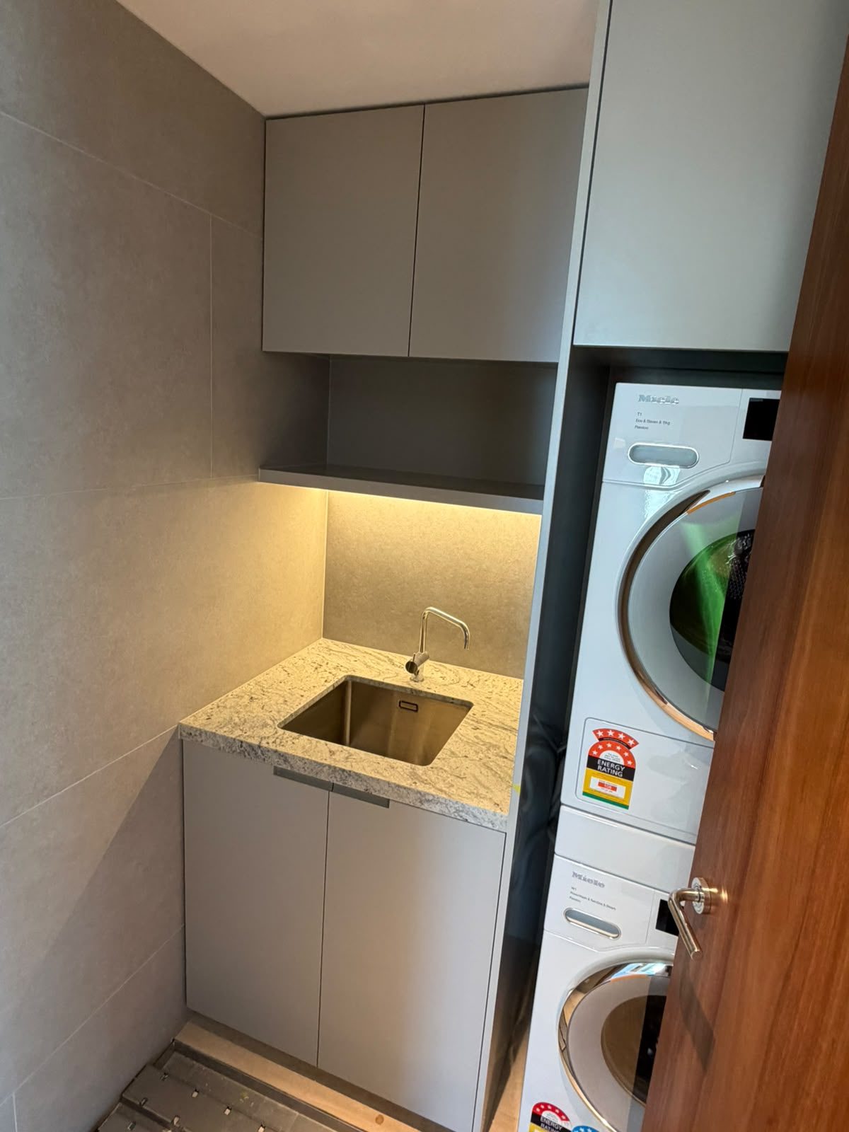 Laundry renovation by Alta-Reno Services — stacked washer and dryer with cabinetry